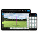 Golf simulator device with screen displaying a golf course and smartphone showing app interface.